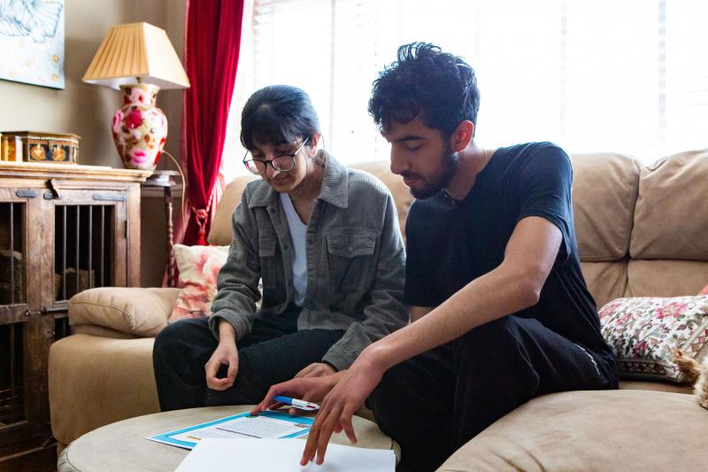Two people looking at documents together on a living room table.